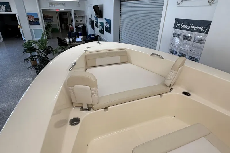 Slide: The Image of 2026 Scout 195 Sportfish boat interior with cushioned seating in showroom. - 11
