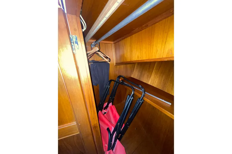 Slide: The Image of Wooden closet interior on 1982 Grand Banks 32 Sedan boat, with hangers and folded chair. - 25