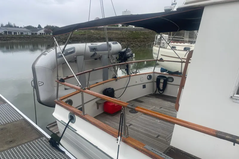 Slide: The Image of 1982 Grand Banks 32 Sedan with dinghy, docked by calm waters. - 40