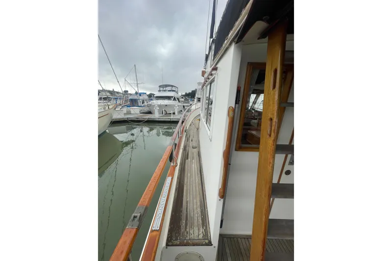 Slide: The Image of 1982 Grand Banks 32 Sedan docked at marina, showcasing wooden deck and railing. - 44