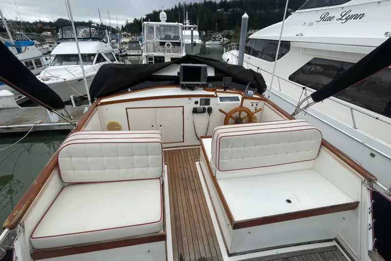 Slide: The Image of 1982 Grand Banks 32 Sedan boat interior with white seating and wooden steering wheel. - 46