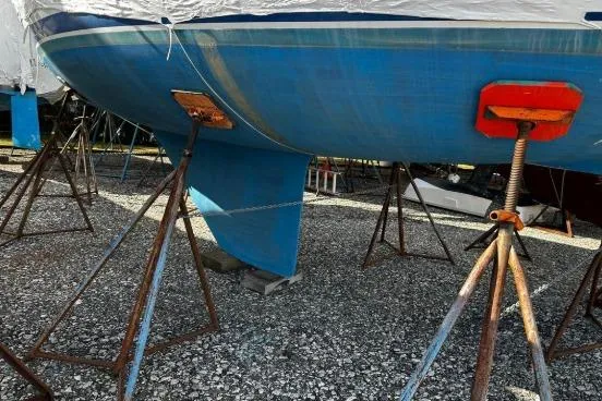 Slide: The Image of 1997 Catalina 28 MkII sailboat on stands, blue hull, gravel ground. - 3