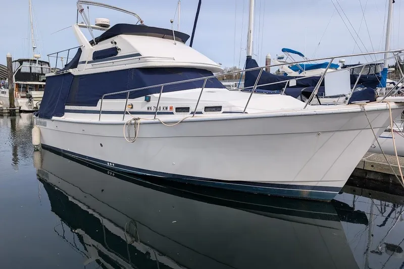 The Image of 1986 Bayliner 3270 Motoryacht docked in marina, featuring blue canvas covers. - 0