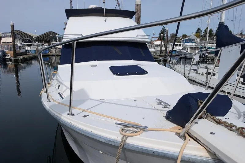 Slide: The Image of 1986 Bayliner 3270 Motoryacht docked at marina, featuring sleek white design and blue accents. - 2