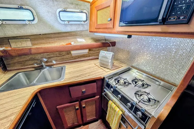 Slide: The Image of 1986 Bayliner 3270 Motoryacht kitchen with stove, sink, and microwave in compact layout. - 21