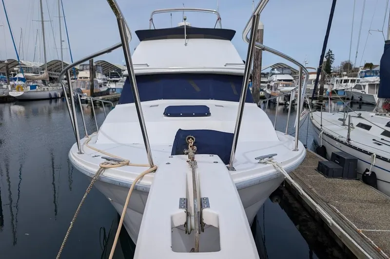 Slide: The Image of 1986 Bayliner 3270 Motoryacht docked at marina, front view with ropes and railings. - 3