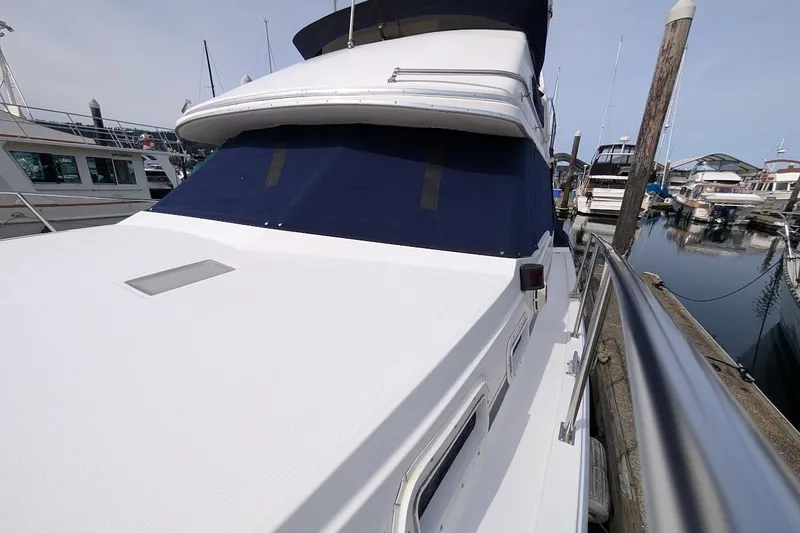 Slide: The Image of 1986 Bayliner 3270 Motoryacht docked at marina, showcasing sleek design and spacious deck. - 5