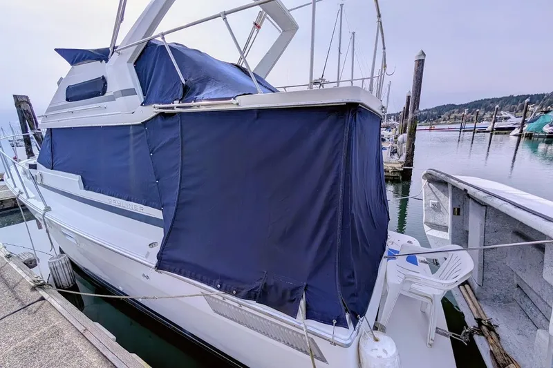 Slide: The Image of 1986 Bayliner 3270 Motoryacht docked with blue canvas cover, marina background. - 7