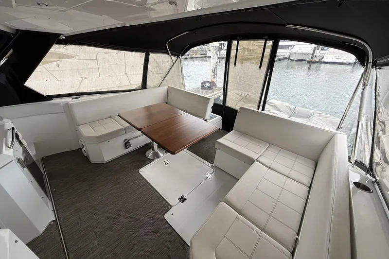 Slide: The Image of 2017 Cruisers Yachts 390 Express Coupe interior with seating and table, docked by the water. - 10