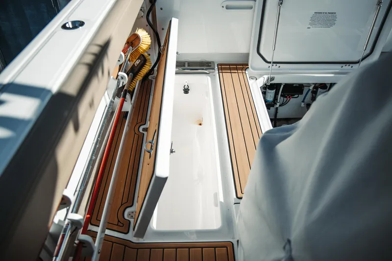 Slide: The Image of 2024 Everglades 315 Center Console boat interior with open storage compartment and teak flooring. - 60