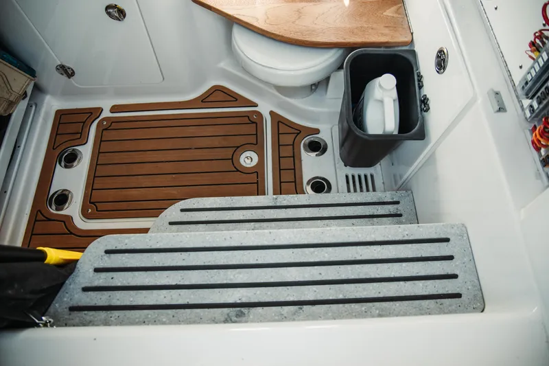 Slide: The Image of 2024 Everglades 315 Center Console interior with wooden flooring and compact toilet area. - 61