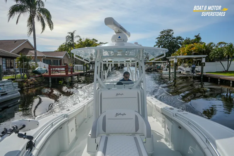 Slide: The Image of 2020 Yellowfin 32 Offshore boat navigating a scenic canal with palm trees. - 33
