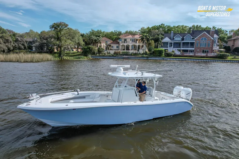 Slide: The Image of 2020 Yellowfin 32 Offshore boat cruising on a scenic river near luxury homes. - 8