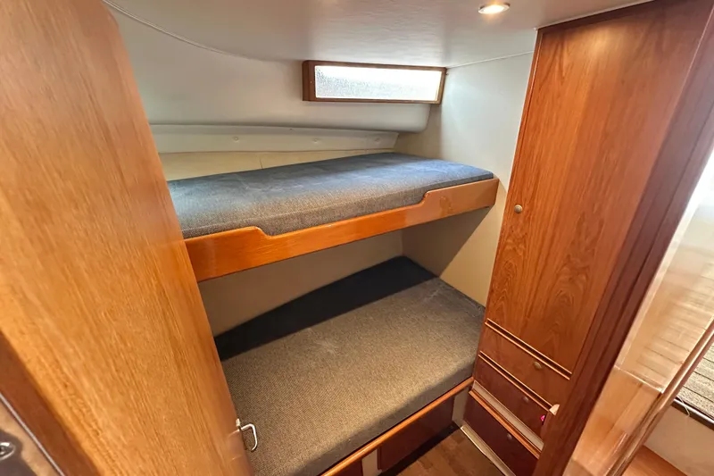 Slide: The Image of Interior of 2002 Skipjack 36 Flybridge with wooden bunk beds and storage. - 11