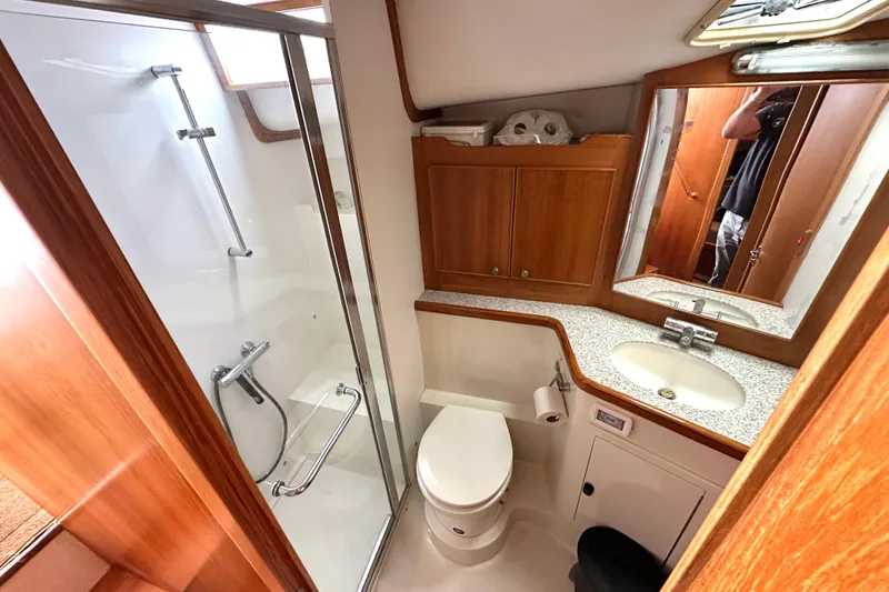 Slide: The Image of 2002 Skipjack 36 Flybridge bathroom with shower, sink, and wooden cabinetry. - 13