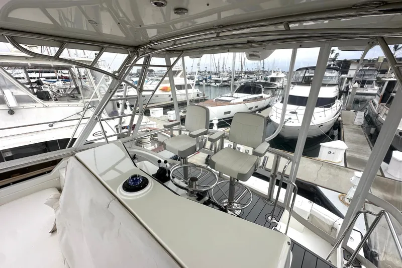 Slide: The Image of Flybridge view of 2002 Skipjack 36, featuring helm chairs and marina backdrop. - 18