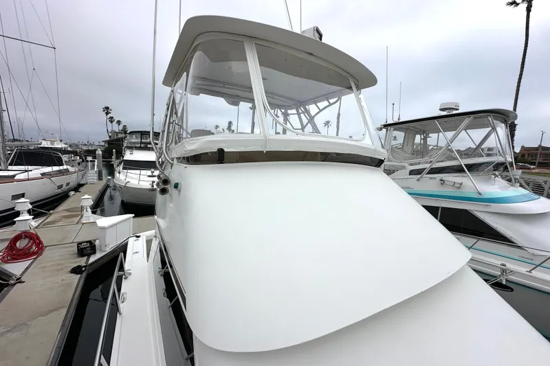 Slide: The Image of 2002 Skipjack 36 Flybridge yacht docked at marina, overcast sky. - 2