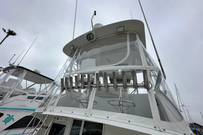 Slide: The Image of 2002 Skipjack 36 Flybridge boat with clear enclosure and rod holders, docked under cloudy skies. - 3