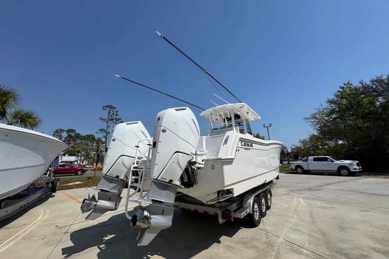 Slide: The Image of 2025 Caymas 34 CT boat with dual outboard motors on a trailer, under clear blue sky. - 13