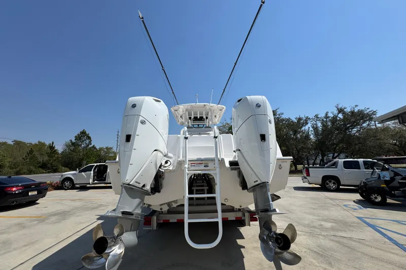 Slide: The Image of 2025 Caymas 34 CT boat with dual outboard engines, parked in a sunny lot. - 15