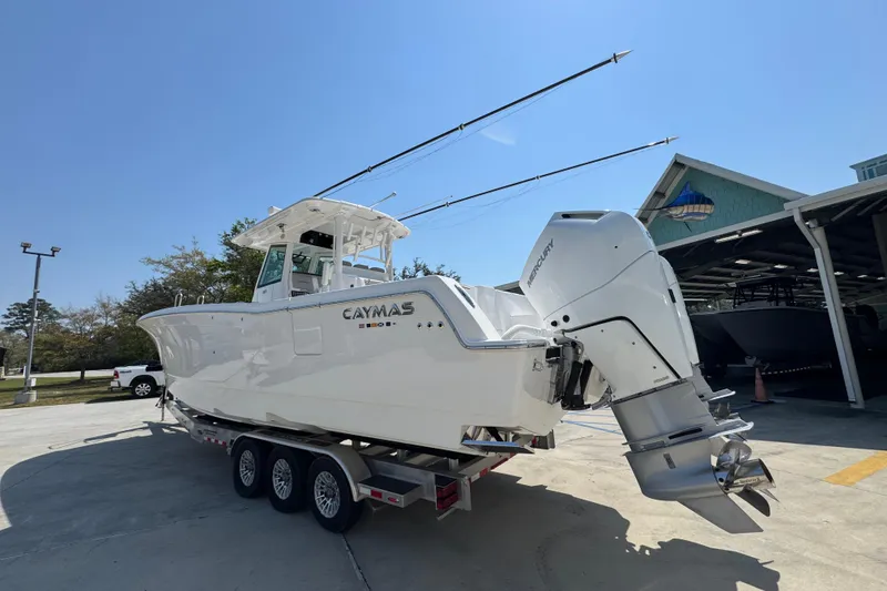 Slide: The Image of 2025 Caymas 34 CT boat on trailer with dual Mercury engines, parked outdoors. - 17