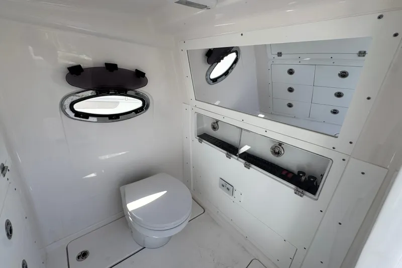 Slide: The Image of 2025 Caymas 34 CT boat interior bathroom with toilet, mirror, and storage compartments. - 28
