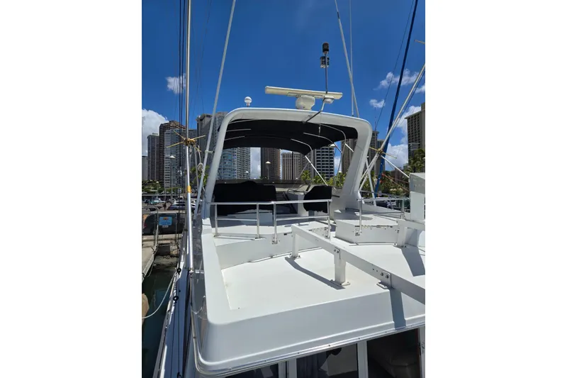 Slide: The Image of 1994 Navigator 5600 yacht docked in marina, city skyline in background, clear blue sky. - 5