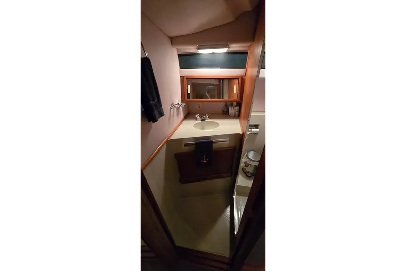Slide: The Image of 1987 Sea Ray 340 Sedan Bridge bathroom with sink, mirror, and wooden cabinetry. - 16