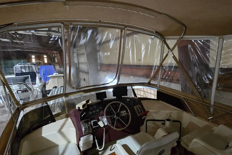 Slide: The Image of 1987 Sea Ray 340 Sedan Bridge interior with helm, docked in a covered marina. - 5