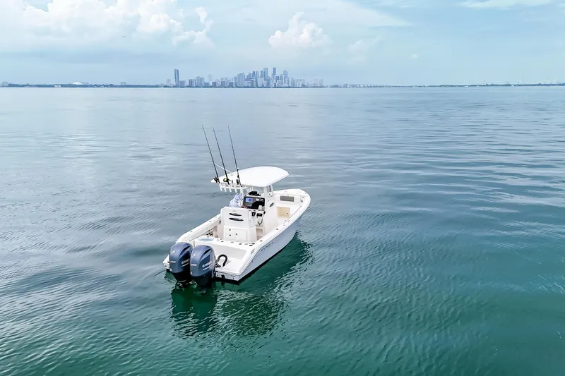 The Image of 2023 Cobia 240 Center Console boat on calm water with city skyline in background. - 0