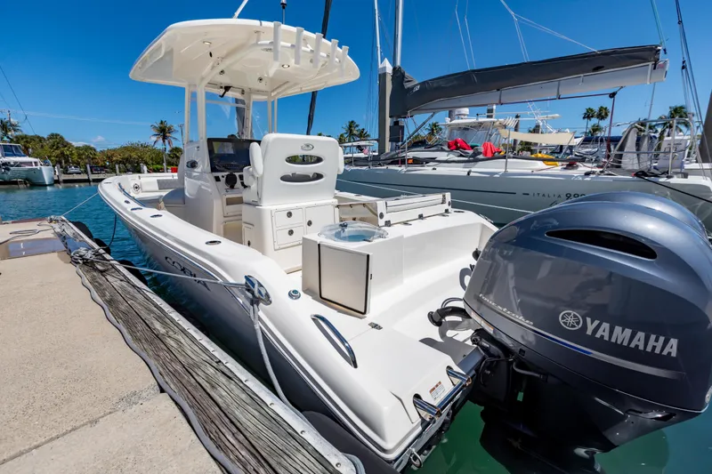 Slide: The Image of 2023 Cobia 240 Center Console boat docked with Yamaha engine, sunny marina setting. - 11