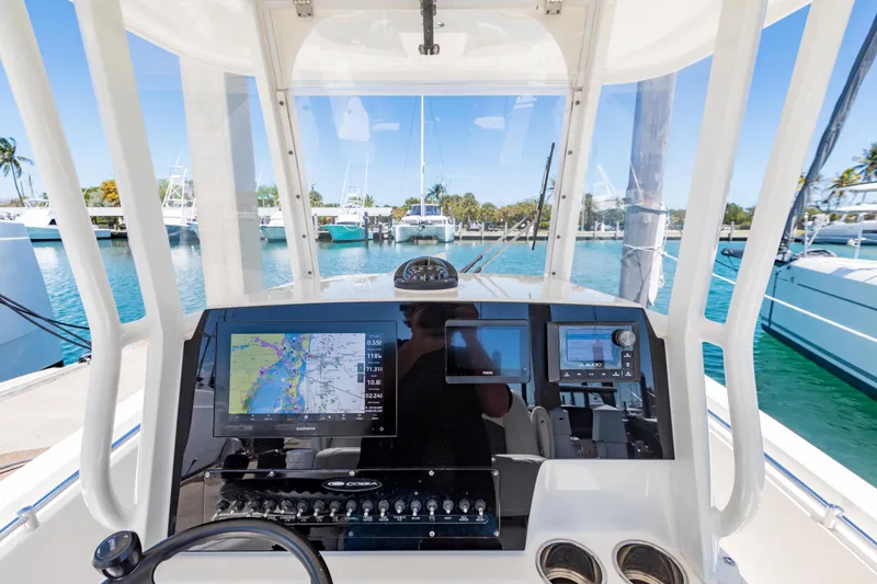 Slide: The Image of 2023 Cobia 240 Center Console boat dashboard with navigation screens and marina view. - 21