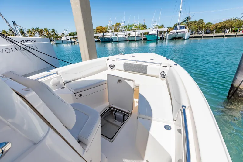 Slide: The Image of 2023 Cobia 240 Center Console boat docked in a marina, showcasing seating and storage. - 26