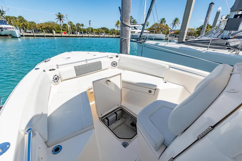 Slide: The Image of 2023 Cobia 240 Center Console boat interior with seating and storage, docked in a marina. - 29