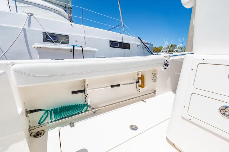 Slide: The Image of 2023 Cobia 240 Center Console boat interior with storage compartment and cleaning hose. - 32