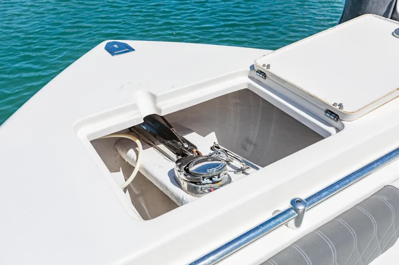 Slide: The Image of 2023 Cobia 240 Center Console boat anchor compartment with open hatch, on blue water. - 33
