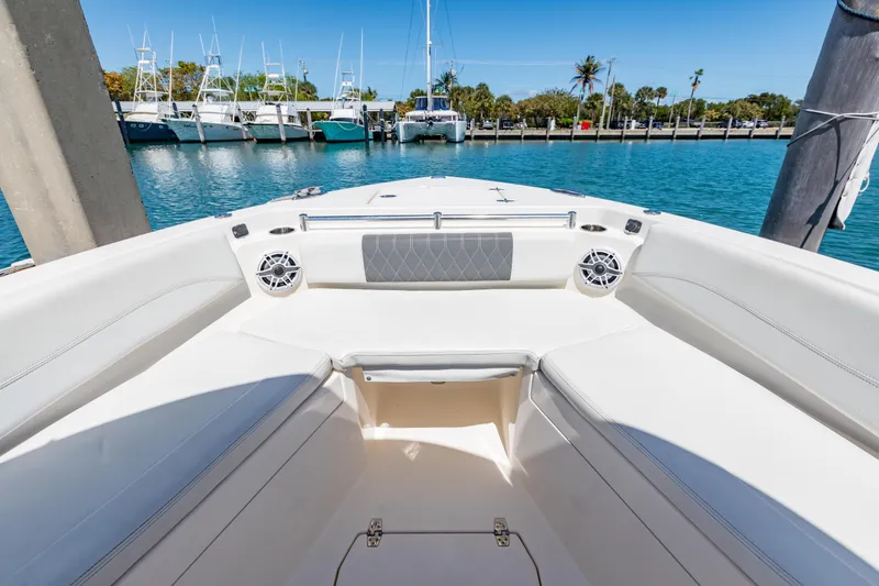 Slide: The Image of 2023 Cobia 240 Center Console boat interior with seating, speakers, and marina view. - 34