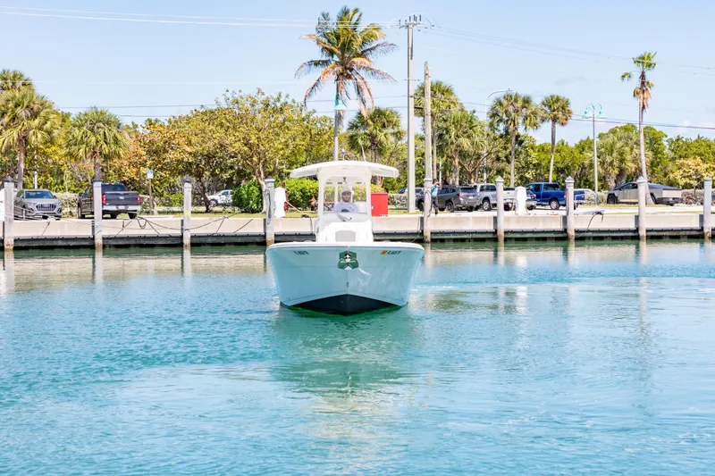 Slide: The Image of 2023 Cobia 240 Center Console boat on calm water near a dock with palm trees. - 4