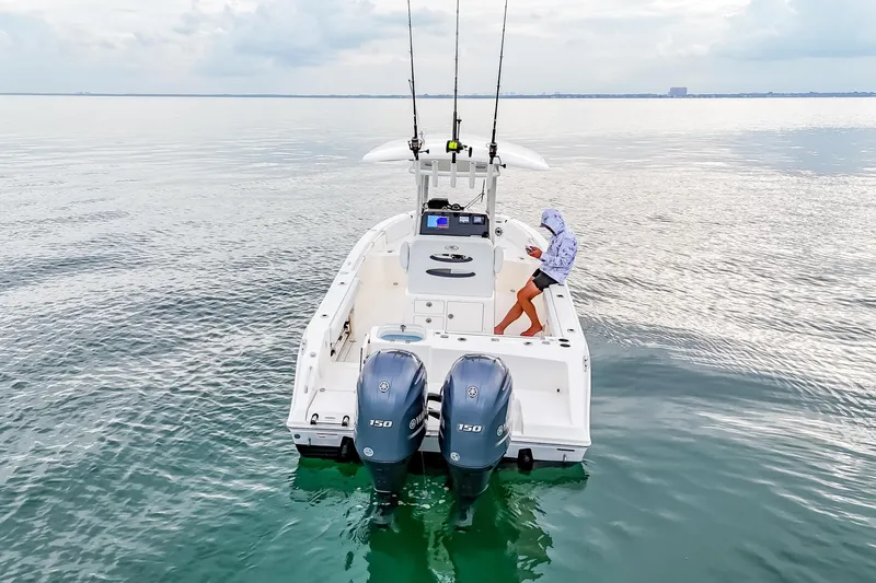 Slide: The Image of 2023 Cobia 240 Center Console boat on calm water with dual engines and fishing gear. - 6