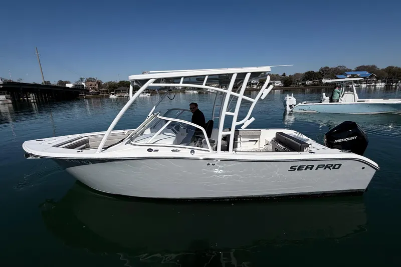 Slide: The Image of 2024 Sea Pro 240 Dual Console boat on calm water, featuring sleek design and Mercury engine. - 11