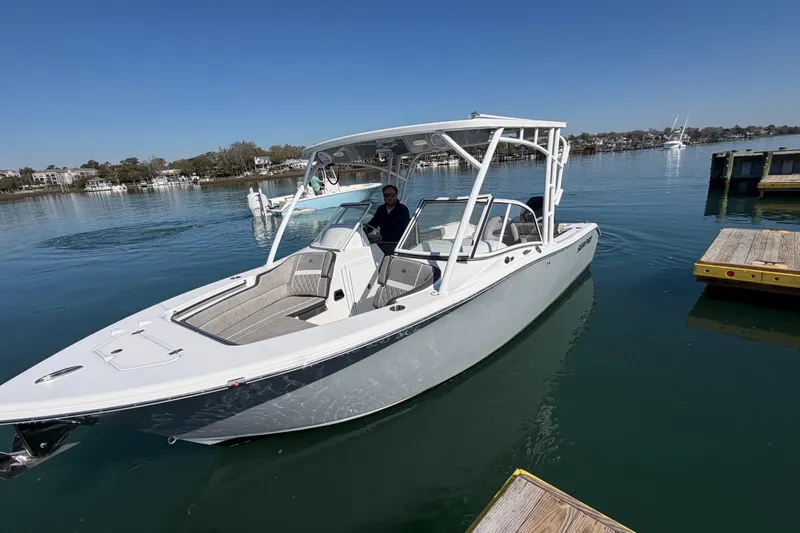 Slide: The Image of 2024 Sea Pro 240 Dual Console boat docked on calm water under clear blue sky. - 12