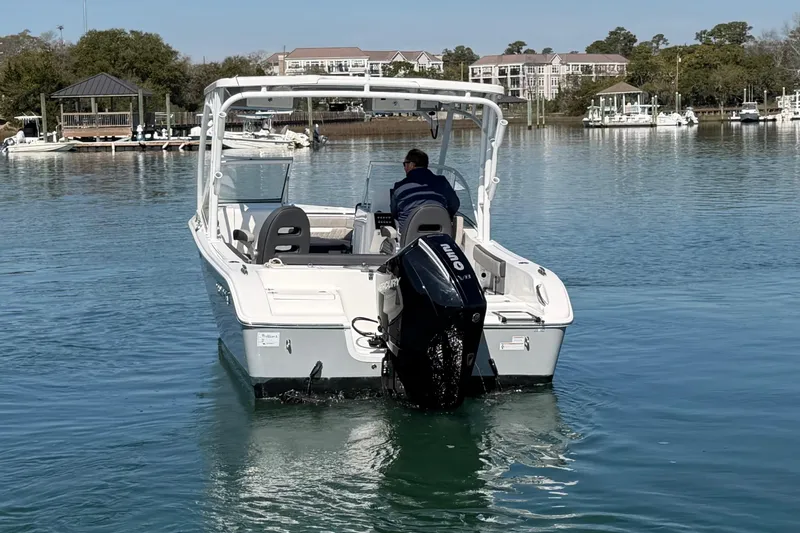 Slide: The Image of 2024 Sea Pro 240 Dual Console boat cruising on calm waters near a marina. - 14