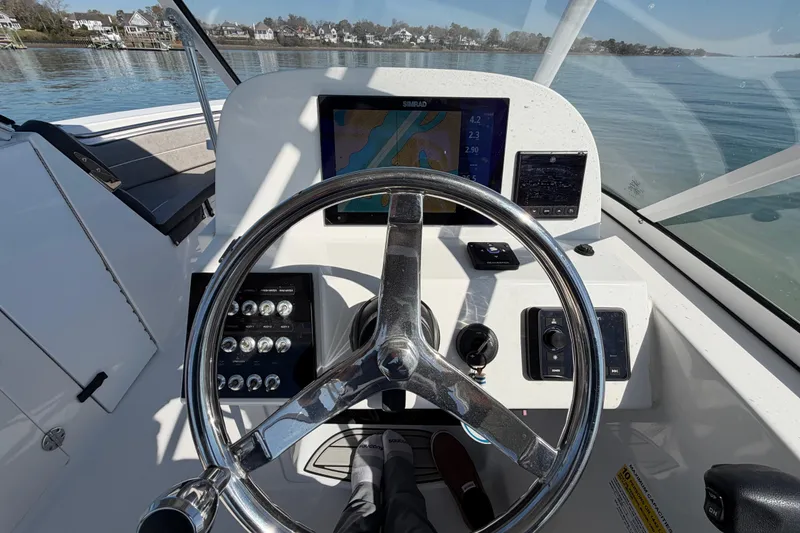 Slide: The Image of 2024 Sea Pro 240 Dual Console boat dashboard with steering wheel and navigation display. - 30