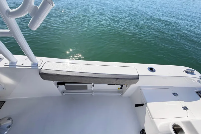 Slide: The Image of 2024 Sea Pro 240 Dual Console boat interior with seating and rod holders on calm water. - 55
