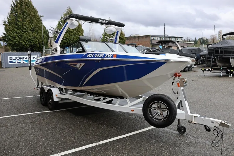 Slide: The Image of 2023 Tigé Z3 boat on trailer in parking lot, blue and white design. - 10