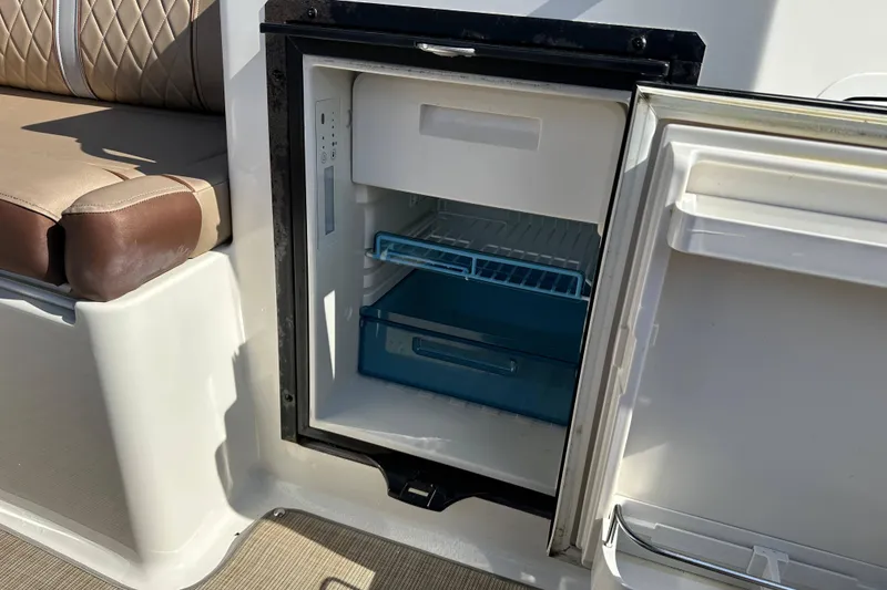 Slide: The Image of Open mini fridge on 2017 Sea Ray SDX 290 Outboard boat, next to cushioned seating. - 28