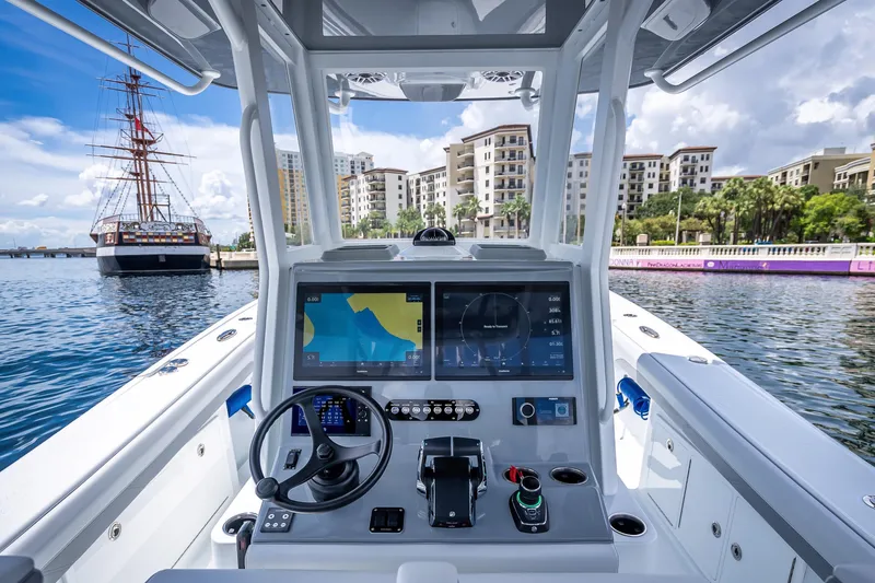 Slide: The Image of 2025 Yellowfin 36 Offshore boat cockpit with modern navigation system, docked near waterfront buildings. - 29