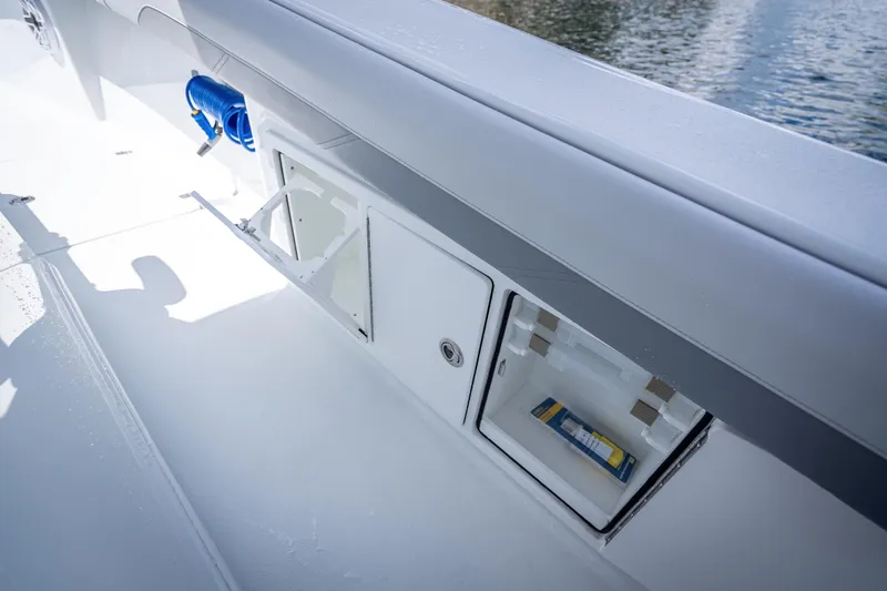 Slide: The Image of 2025 Yellowfin 36 Offshore boat storage compartments with water hose and tackle box. - 34