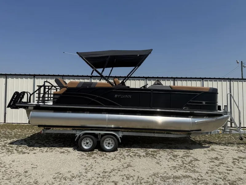 The Image of 2026 Sylvan L-3 LZ DH pontoon boat on trailer outside warehouse. - 1
