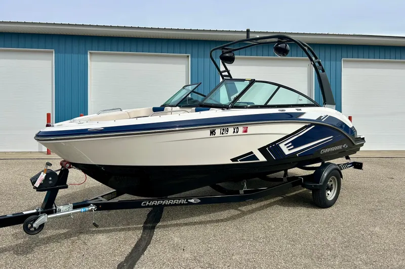 Slide: The Image of 2017 Chaparral 203 Vortex boat on trailer, parked near blue building. - 1